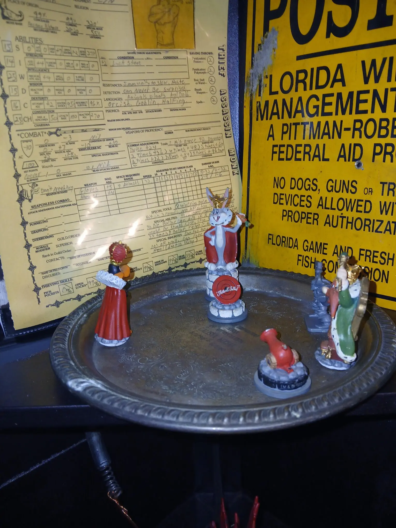 Miniature figurines posed on a circular platform with a yellow sign in the background.